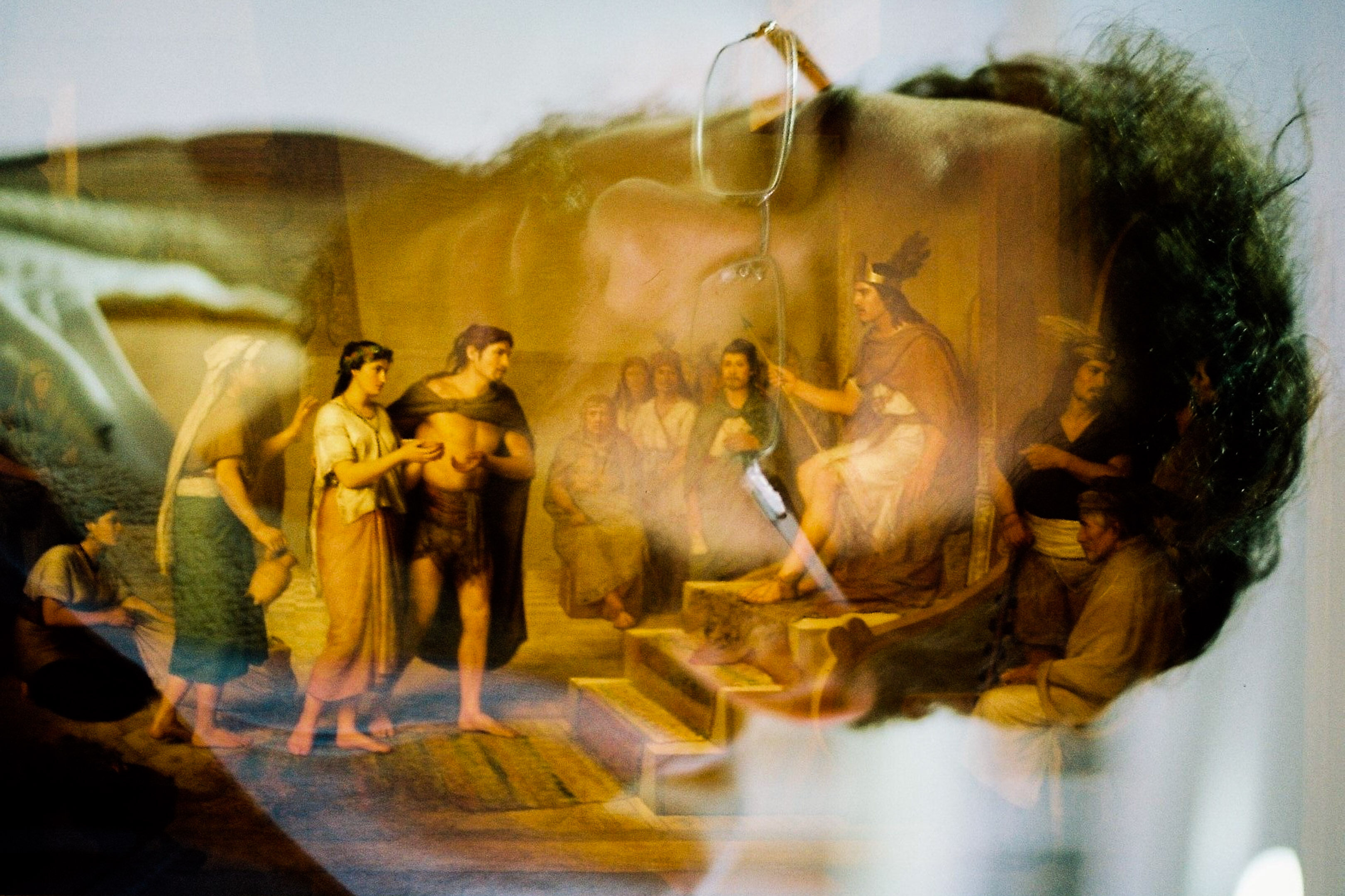 Double exposed image of a painting of aztec history and man with glasses