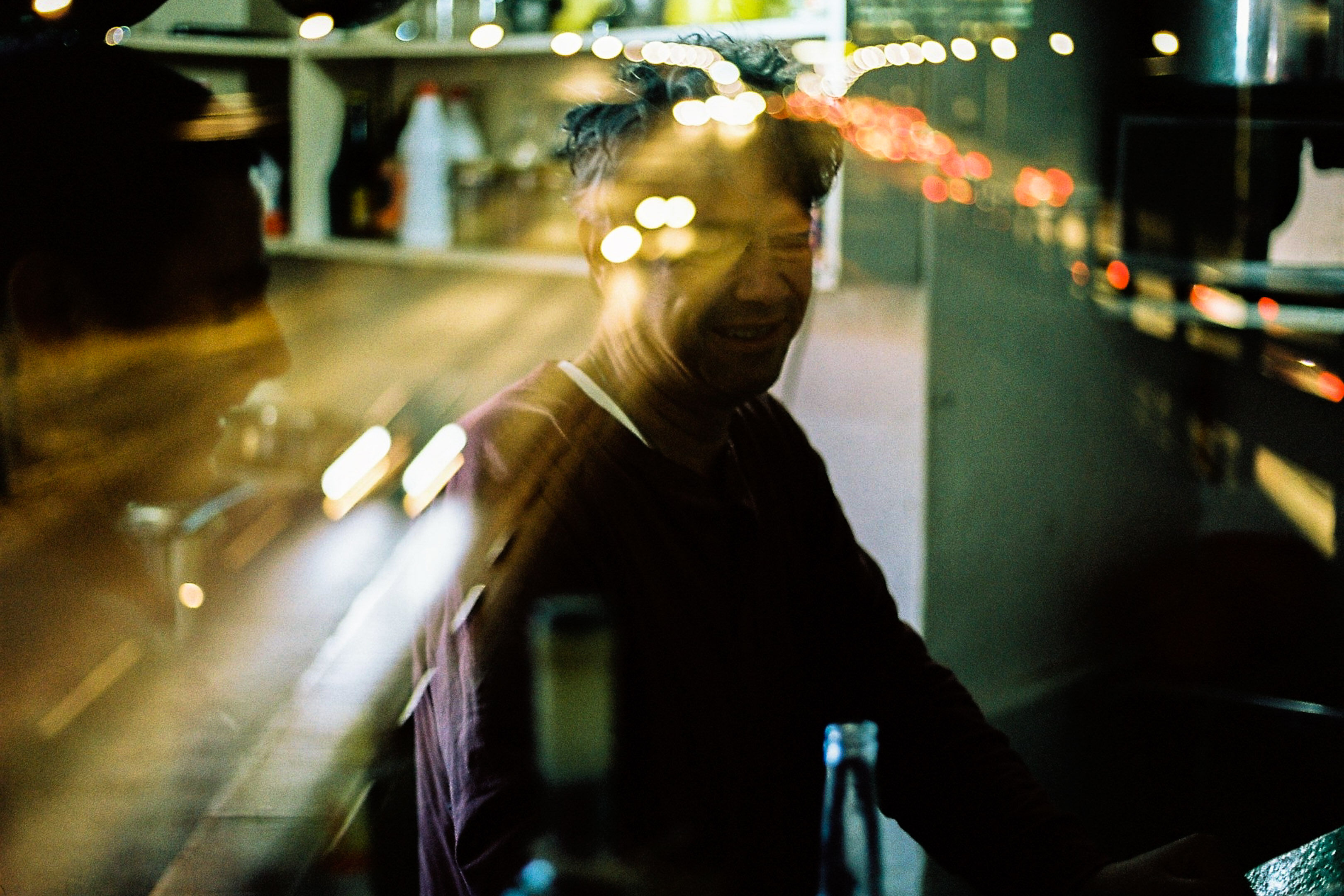 Double exposed image of drunk man inside a cantina and an overlay of a distorted highway at night