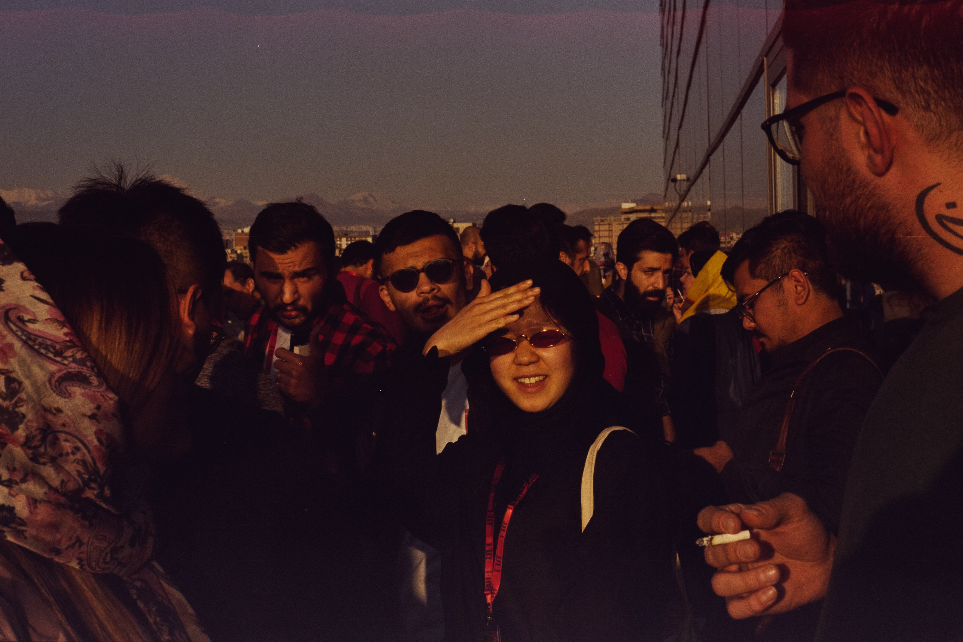 Woman with sunglasses in the sun with other people on a balcony